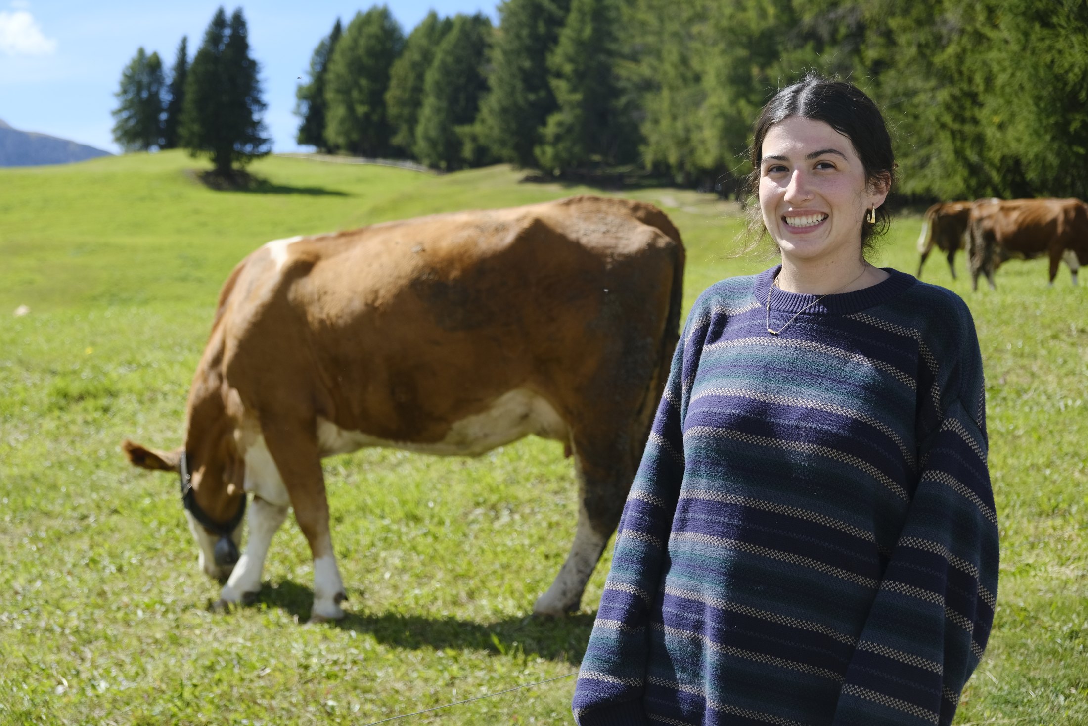 Noa smiling in a green mountain meadow